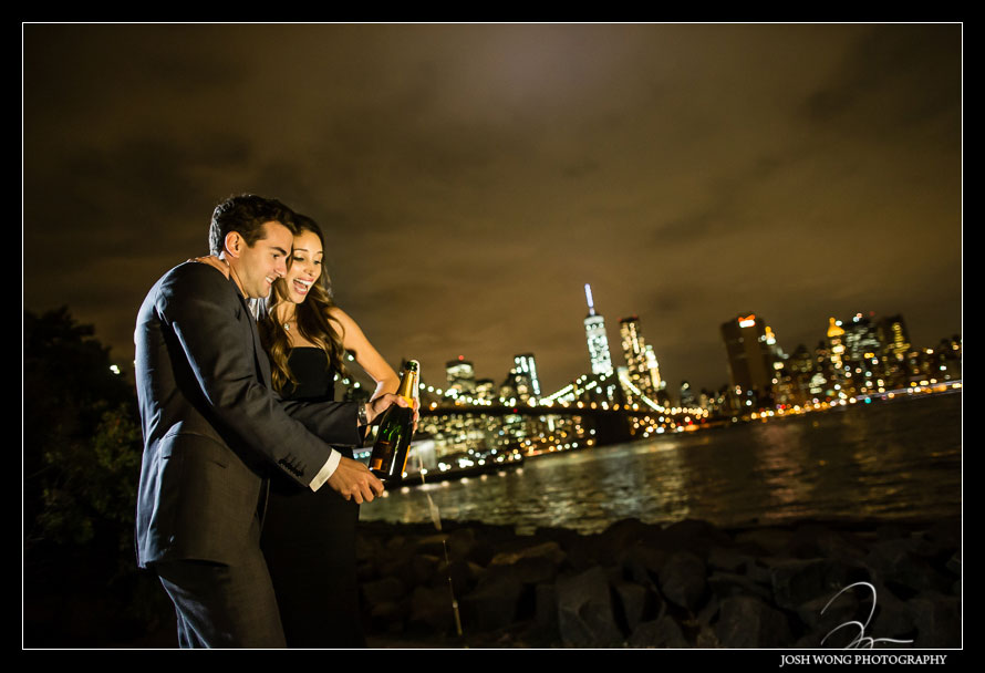 The couple toasting with champaign in an intimate nighttime engagement photoshoot in DUMBO Brooklyn with top engagement and wedding photographer Josh Wong Photography. Best Engagement pictures in New York City.