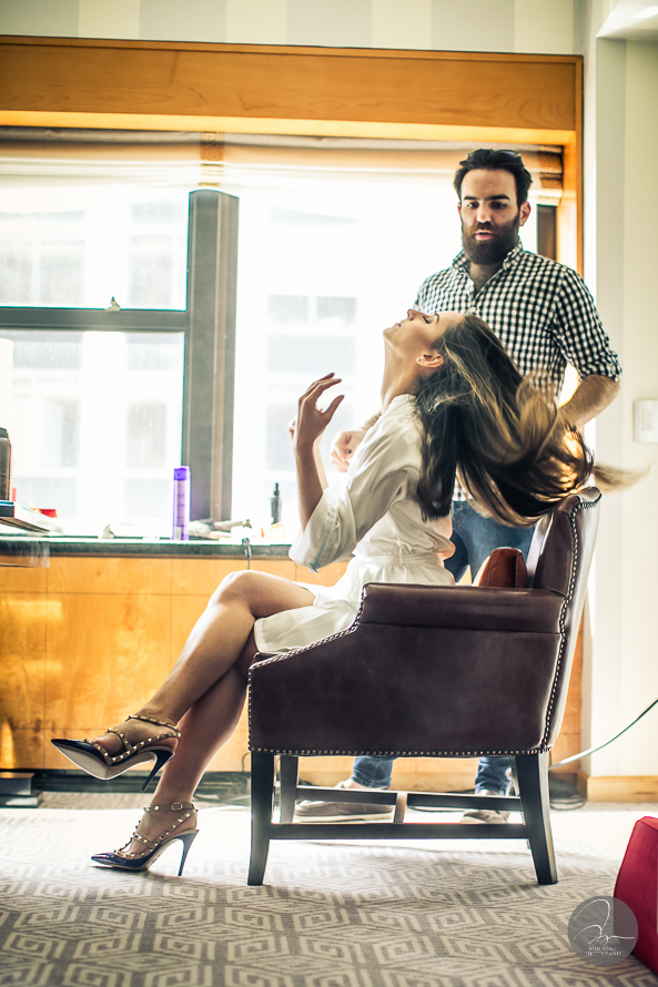 Bride is getting her hair and makeup done in the bridal suite of the wedding venue.