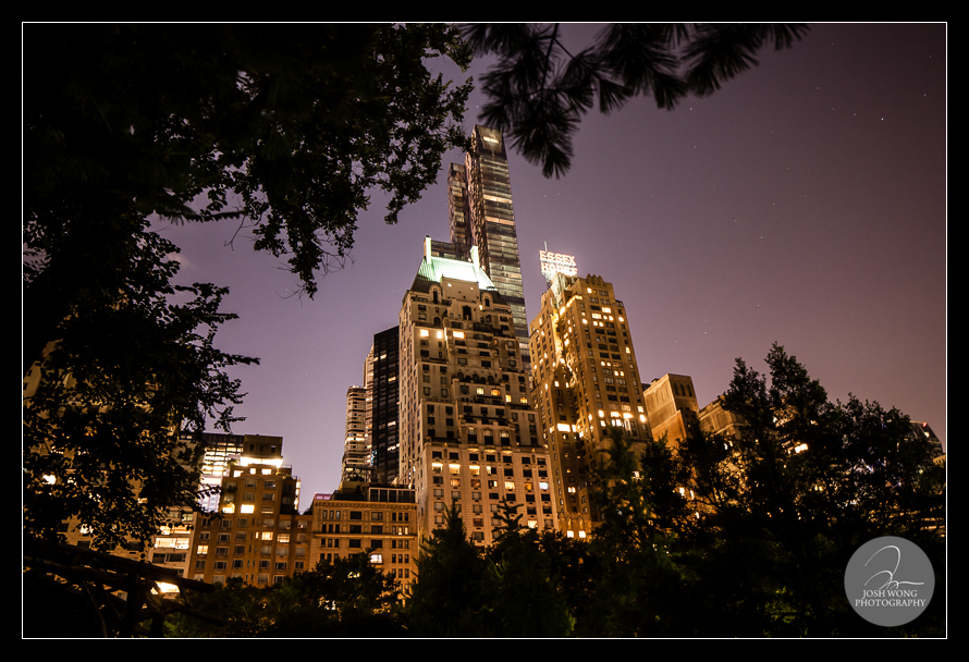The iconic tower of the Essex House take in the evening from within Central Park.