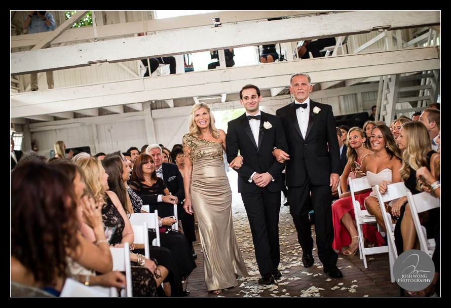 The groom escorted out by his parents.