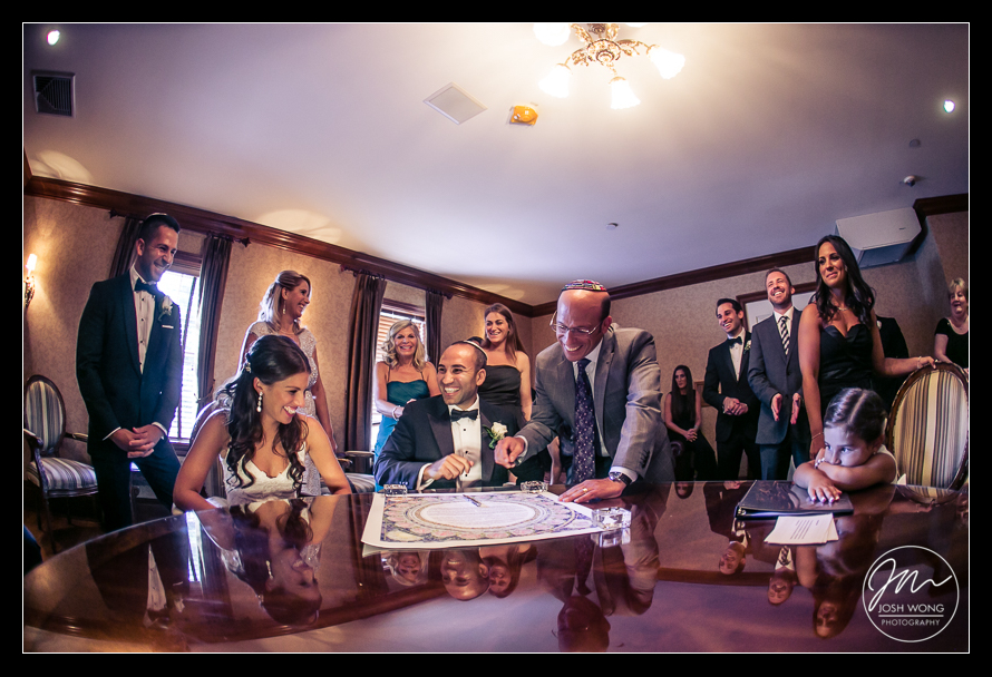 A joyous moment of laughter during the ketubah signing. Royalton Mansion Wedding by Josh Wong Photography