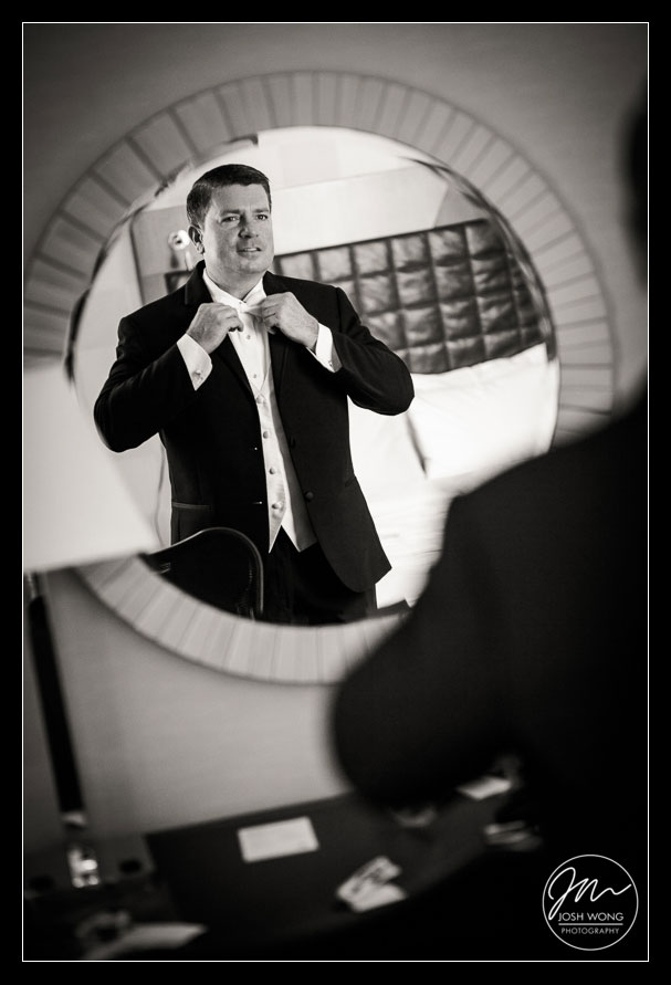The adjusting his bow tie just before he sees his bride for the first look. 