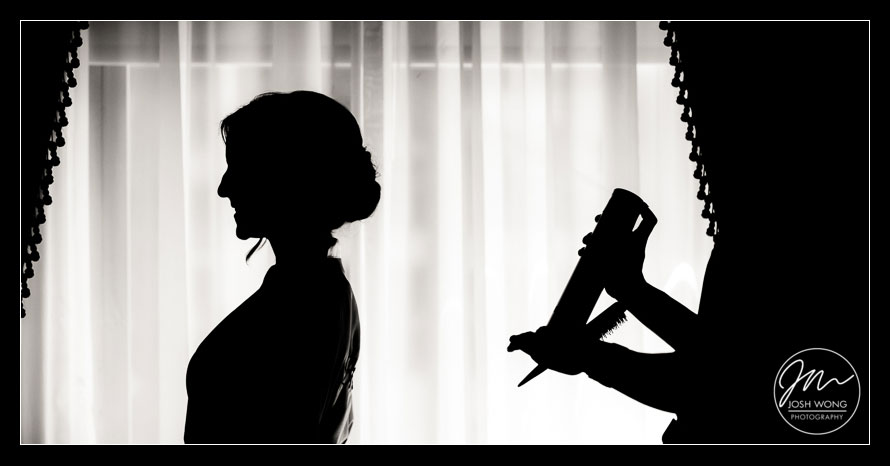 A silhouette  photograph with the bride getting a dose of hair spray to finalize her look. photos by Josh Wong Photography