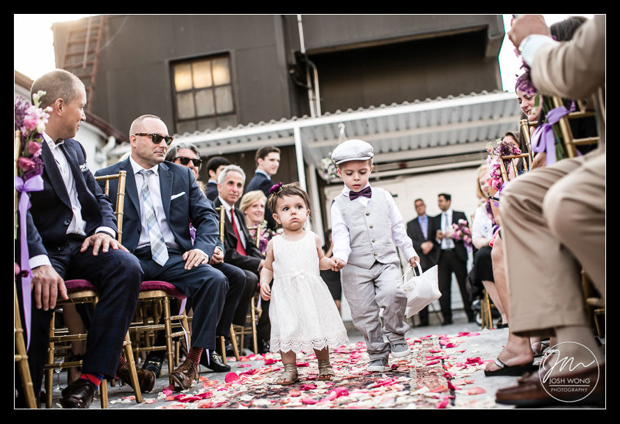 The ring bearer and flower girl escort each other down the aisle. Studio 450 Rooftop Wedding by Josh Wong Photography
