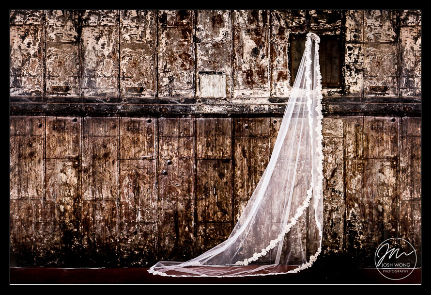 The gorgeous veil of the bride on display hung on the textured vintage freight elevator door. Photo by Josh Wong Photography