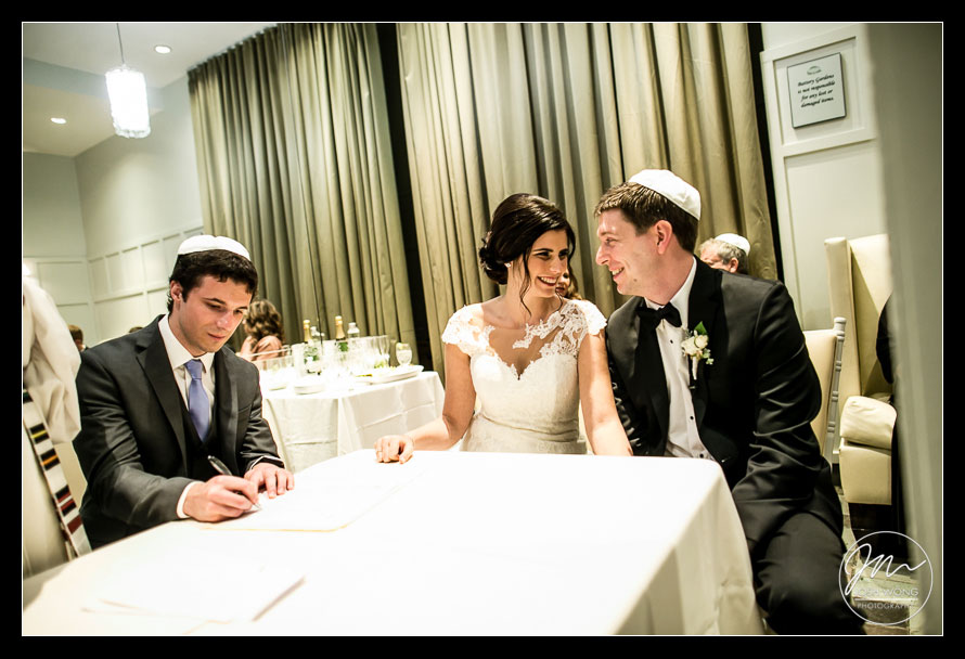 The wedding couple sign the ketubah ahead of their Jewish wedding at The View at The Battery.