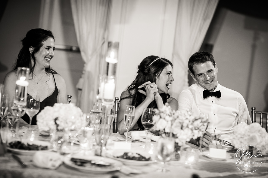 The newlyweds laugh at the Maid of Honor and Best Man speeches. 