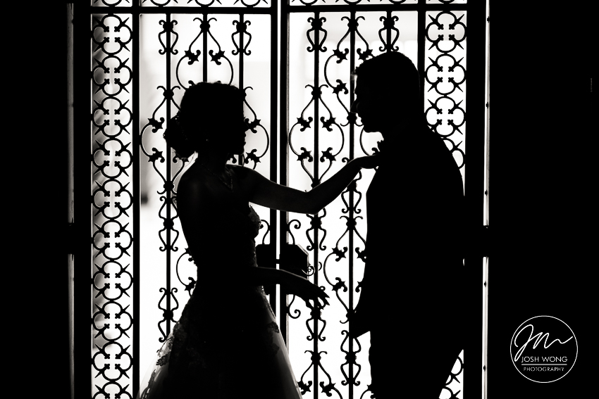 A silhouette photo in front of wrought iron gates at the Pleasantdale Chateau by NJ wedding photographer Josh Wong