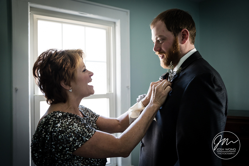 Mother of the groom helps attach the boutonniere to the grooms lapel.