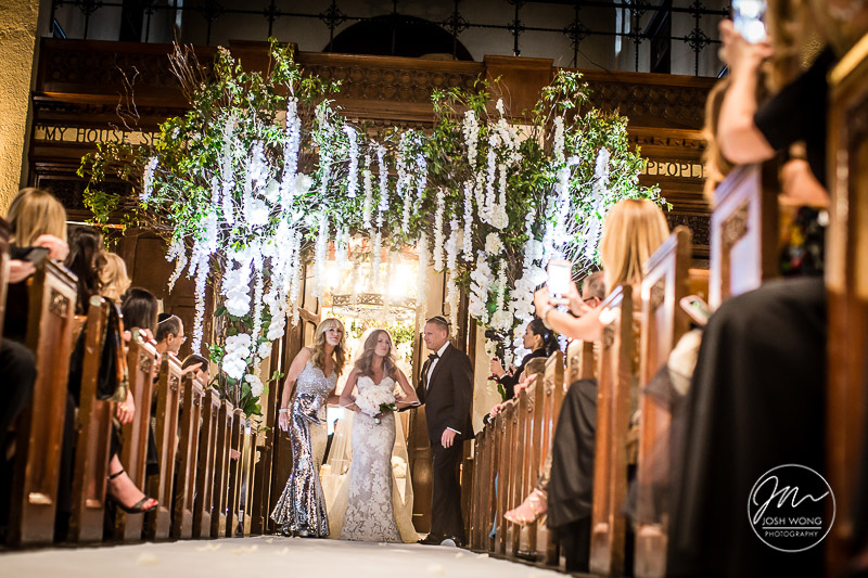 Guest all see the bride for the first time walking down the aisle. A Jewish wedding at the Temple of Israel in Lawrence, NY by top New York Wedding Photographers Josh Wong Photography