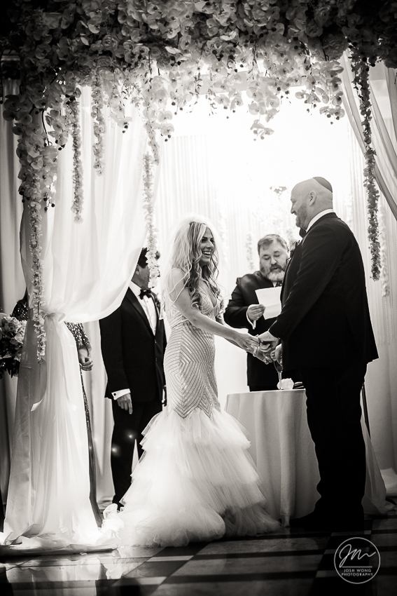 In the moment with the bride and groom exchanging nuptials. Best wedding candid moments at The Venetian in Garfield, NJ. Wedding photos by Josh Wong Photography