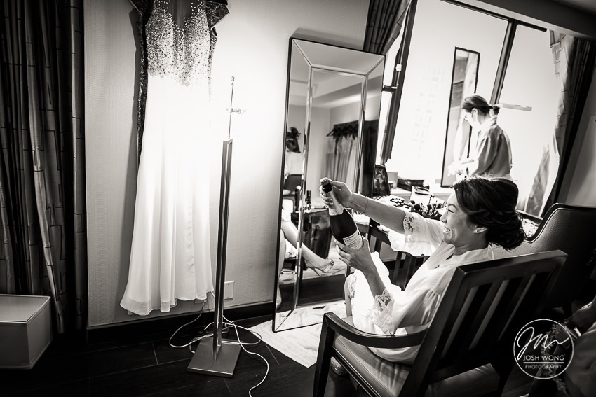 The bride getting ready by popping the cork on a bottle of champagne.