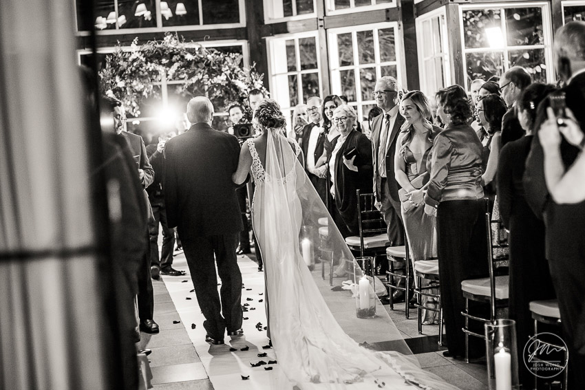 The Father of the bride escorts the bride down the aisle. Wedding photography by NYC wedding photographer Josh Wong. Central Park Boathouse.