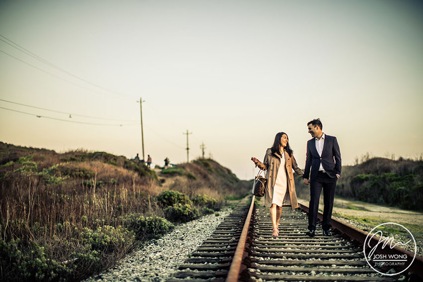 The engaged couple walk along the railroad tracks in Santa Cruz California 