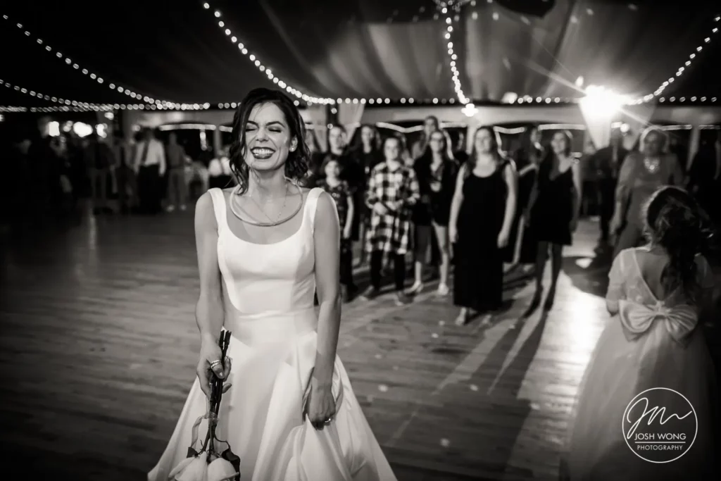 The bouquet toss. Best candid moments of the bride during her wedding reception at the Pla Mor Ballroom. Featuring wedding photography by Nebraska top wedding photographer Josh Wong Photography.
