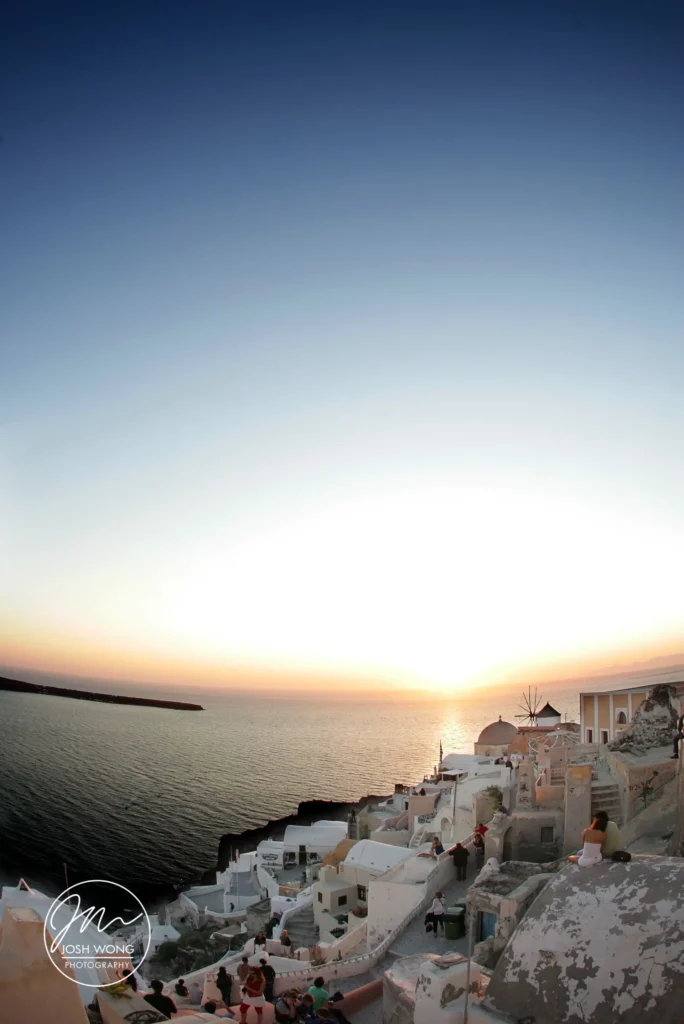 The people gather every night to enjoy the magical Santorini sunset. This sunset is the most gorgeous sunset on the planet. Greece Santorini destination wedding by top international wedding photographer Josh Wong Photography