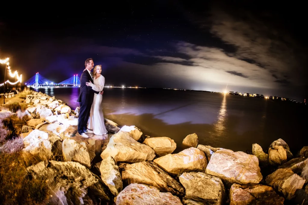Newlyweds Katrina Szish and Marc enjoy an intimate moment on the rocks at Rehoboth Beach in Delaware. Wedding photography by Josh Wong Photography