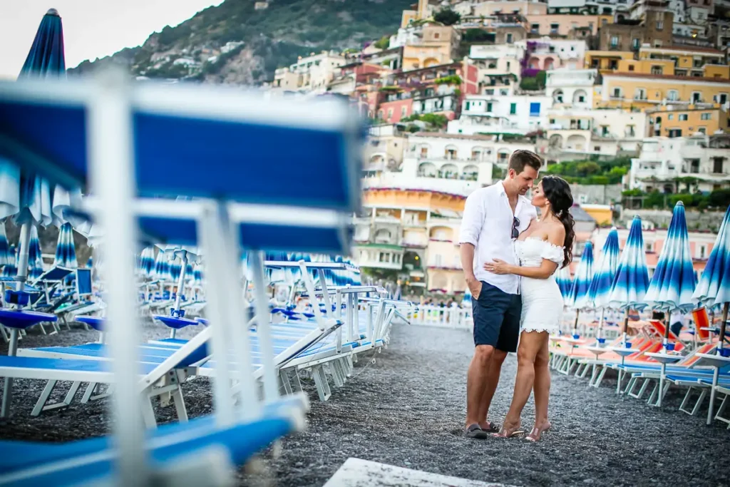 Couple engagement photo taken on Positano Spiaggia with the blue beach umbrellas. 