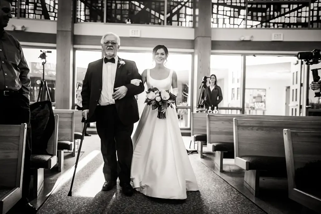 Father of the bride escorts the bride down the wedding aisle. St. Josephs Catholic Church - Lincoln Nebraska Wedding pictures.